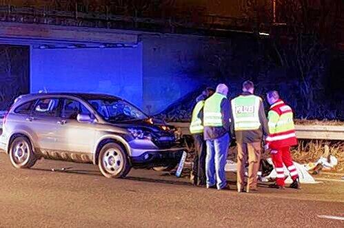 Die Windschutzscheibe des Hondas ist zertrümmert, Helfer stehen um die abgedeckte Leiche am Rand der B4 herum.