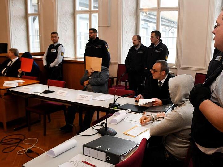 Der Vater (M) wird zusammen mit seinen Söhnen (l und 2.v.r) von Justizwachtmeistern bewacht. Foto: Stefan Puchner/dpa