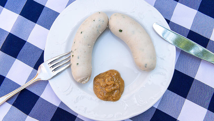 Zwei Stück Weißwürste mit einem Klacks süßem Senf liegen in einem Restaurant auf einem Teller. Zwei Stück Weißwürste mit einem Klacks süßem Senf liegen in einem Restaurant auf einem Teller.