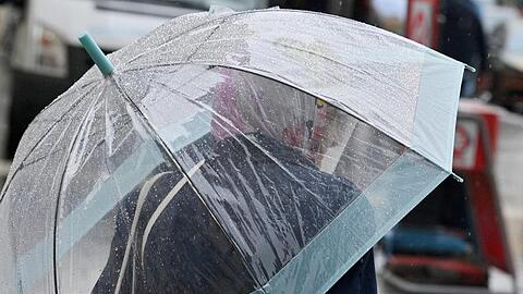 Eine Passantin geht mit einem durchsichtigen Regenschirm durch die Innenstadt. Foto: Peter Kneffel/dpa/Archivbild