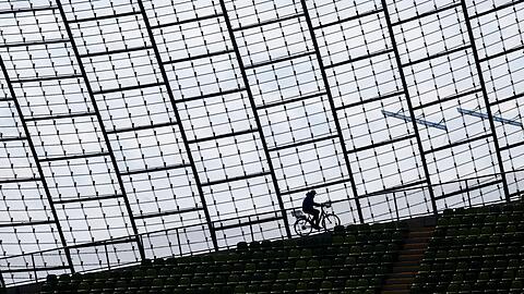 Ein Mitarbeiter des Olympiastadions fährt mit einem Fahrrad am Glasdach der Spielstätte vorbei.