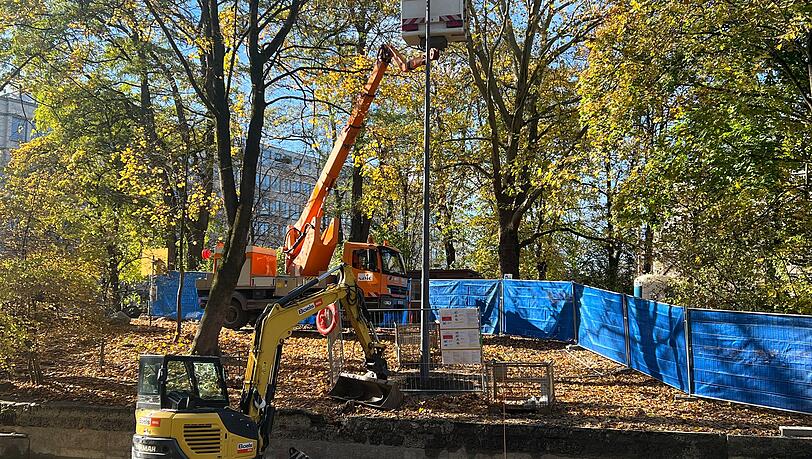 Der 11,33 Meter hohe Lichtmast steht am Eisbach auf der linken Seite in Flussrichtung. Dank einer Zeitschaltuhr soll künftig die Beleuchtung bei Sonnenuntergang angehen.