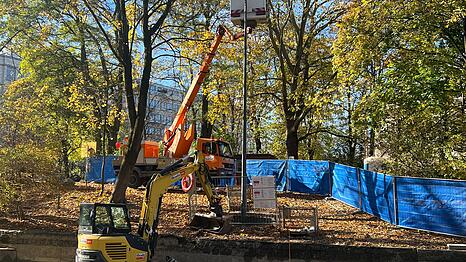 Der 11,33 Meter hohe Lichtmast steht am Eisbach auf der linken Seite in Flussrichtung. Dank einer Zeitschaltuhr soll künftig die Beleuchtung bei Sonnenuntergang angehen.