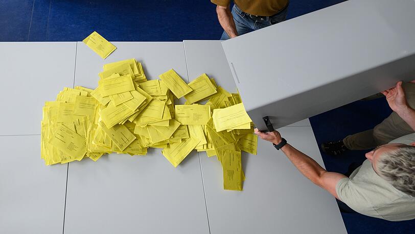 Stimmzettelumschläge für eine Briefwahl werden aus einer Wahlurne geschüttet.