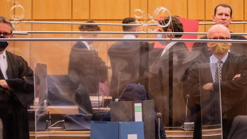 Der damals 27-Jährige Hauptangeklagte (vorne), seine Mutter (ganz hinten links) und ein dritter Angeklagter (roter Hefter) sitzen in einem Gerichtssaal des Landgerichts.