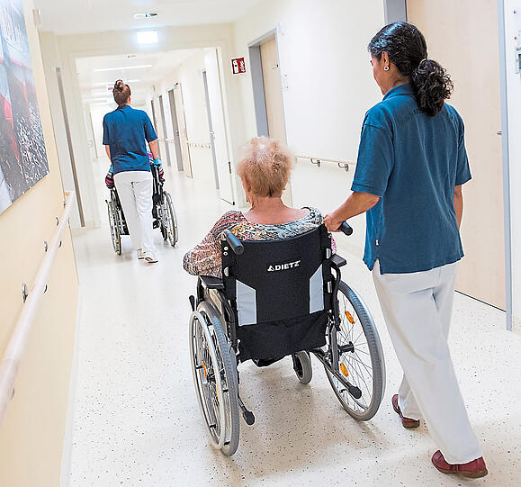 Zwei Schwestern schieben Patienten mit Rollstühlen. Oft beginnt nach der Klinik die Suche nach einem Pflegeplatz.