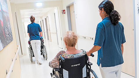 Zwei Schwestern schieben Patienten mit Rollstühlen. Oft beginnt nach der Klinik die Suche nach einem Pflegeplatz.