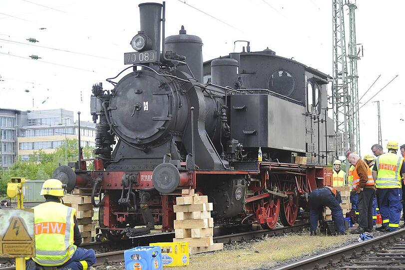 Das THW hebt die alte Lok mit Hydraulik-Geräten an und legt Holzpflöcke unter.