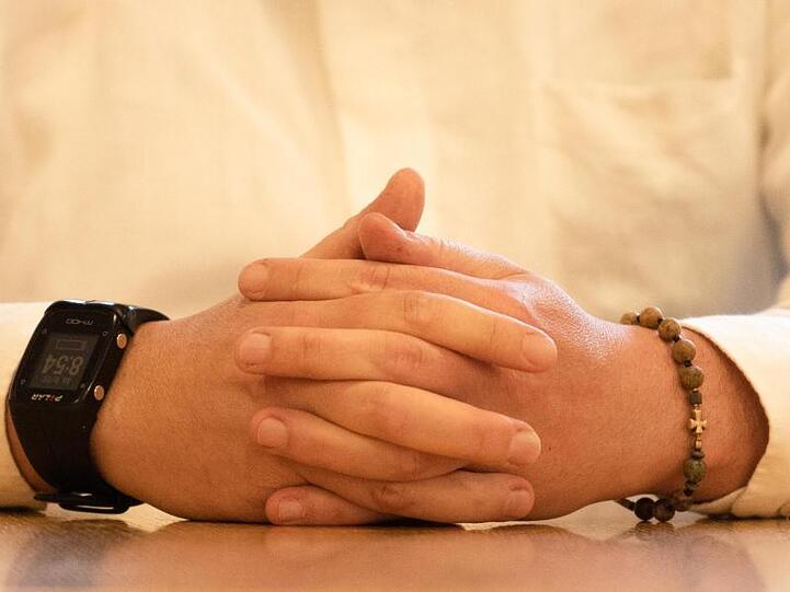 Der angeklagte Priester trägt im Gerichtssaal ein Armband mit einem Kreuz. Foto: Nicolas Armer/dpa Pool/dpa