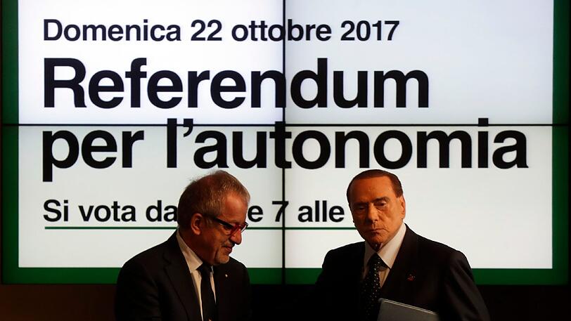 Italiens Ex-Ministerpräsident Silvio Berlusconi und der Präsident der Lombardei Roberto Maroni stehen während einer Pressekonferenz in Mailand zum geplanten Unabhängigkeitsreferendum vor einem Plakat, dass für das Referendum wirbt.