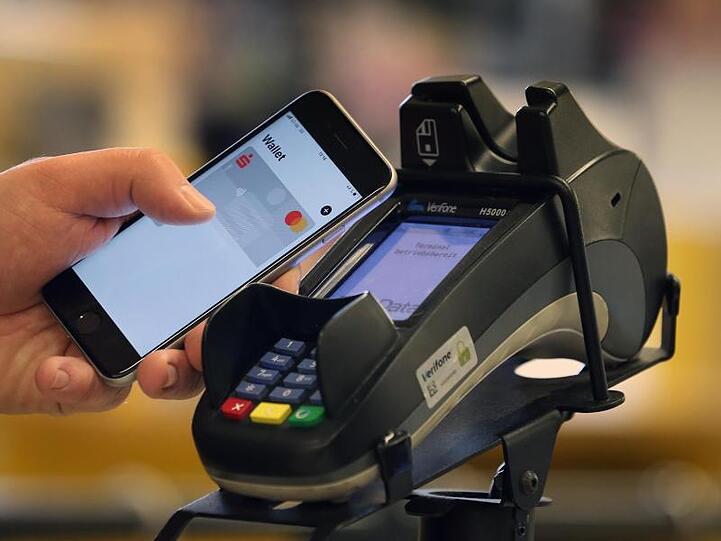 Ein Smartphone wird an den Bezahl-Terminal an der Kasse eines Supermarktes gehalten. Das kontaktlose Bezahlen wird nach Einschätzung der Bundesbank in Deutschland populärer.