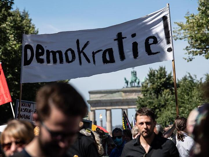 "Demokratie!" steht auf einem Banner, das von Teilnehmern auf der Demonstration gegen die Corona-Beschränkungen vor dem Brandenburger Tor Anfang August getragen wird.