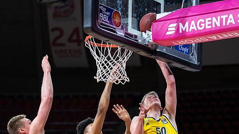 Leon Radosevic (l-r) und Jason George von Bayern München versucht Ben Lammers von Alba Berlin am Korb zu blocken.