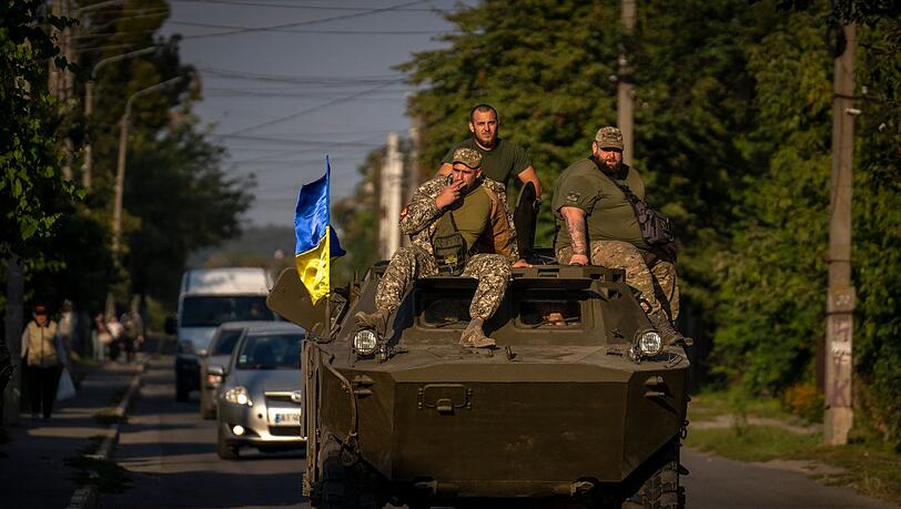 Soldaten der ukrainischen Armee sitzen auf einem gepanzerten Militärfahrzeug.