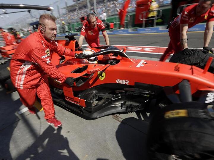 Die Boxencrew von Ferrari schiebt den Rennwagen von Sebastian Vettel in die Boxengasse.