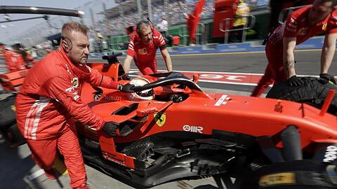 Die Boxencrew von Ferrari schiebt den Rennwagen von Sebastian Vettel in die Boxengasse.