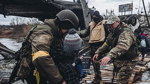 Soldaten helfen einem Kind beim &Uuml;berqueren des Flusses in Irpin unweit von Kiew.