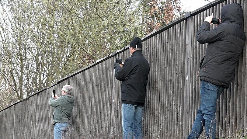 Kirchroth/Bayern: Schaulustige fotografieren neben einer Lärmschutzwand mit ihren Smartphones eine Unfallstelle. Fotos von Unfall-Toten sowie heimliche Aufnahmen unter Röcke und ins Dekolleté sollen härter bestraft werden.