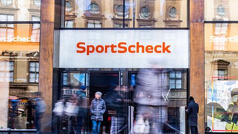 Personen gehen an einer Sportscheck-Filiale in der Münchener Fußgängerzone vorbei.