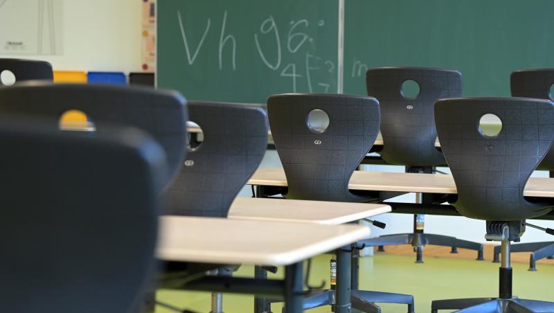 In einem leeren Klassenzimmer sind die Stühle auf die Schulbänke gestellt.