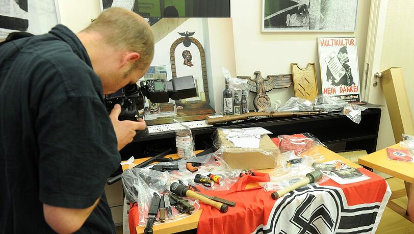 Nach der Razzia in mehreren Objekten, darunter im "braunen Haus" in Obermenzing, werden im Innenministerium beschlagnahmte Waffen, Hakenkreuz-Fahnen, Propagandamaterial und weitere Nazi-Devotionalien präsentiert. Nach der Razzia in mehreren Objekten, darunter im "braunen Haus" in Obermenzing, werden im Innenministerium beschlagnahmte Waffen, Hakenkreuz-Fahnen, Propagandamaterial und weitere Nazi-Devotionalien präsentiert.