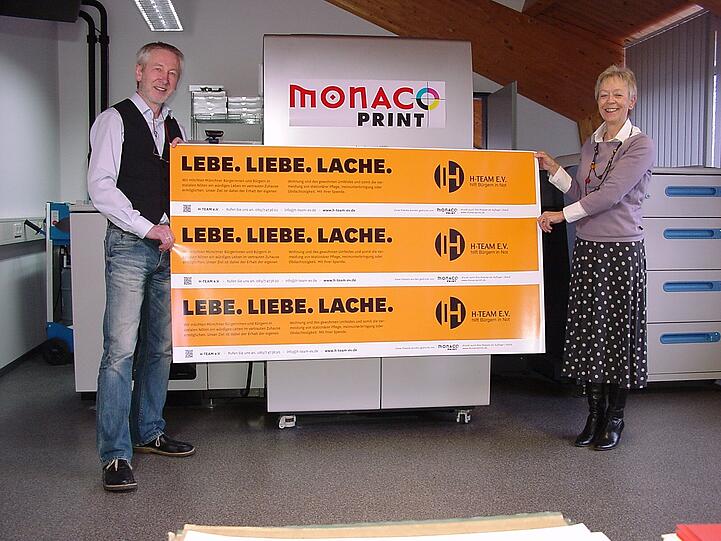 Geschäftsführer Hans-Otto Böhmert von Monaco Print und seine Mitarbeiterin Christine Lehmann drucken kostenlos 200 Plakate für den H-TEAM e.V.