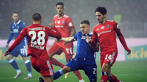 Der Karlsruher Marco Thiede (M) kämpft mit den Hamburgern Miro Muheim (l) und Ludovit Reis um den Ball.