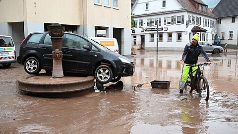 Auf einem Brunnen in Rudersberg steht ein durch Hochwasser weggespültes Auto.