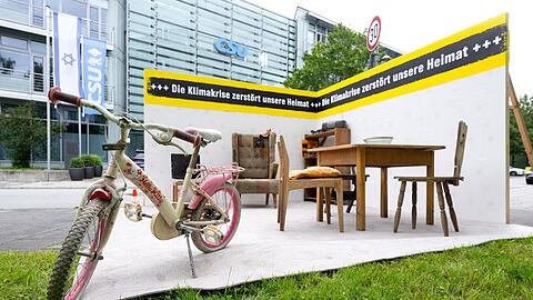 Aktivisten von Greenpeace haben vor der CSU Parteizentrale ein Zimmer voller zerstörter Möbel aus den Flutgebieten aufgebaut.