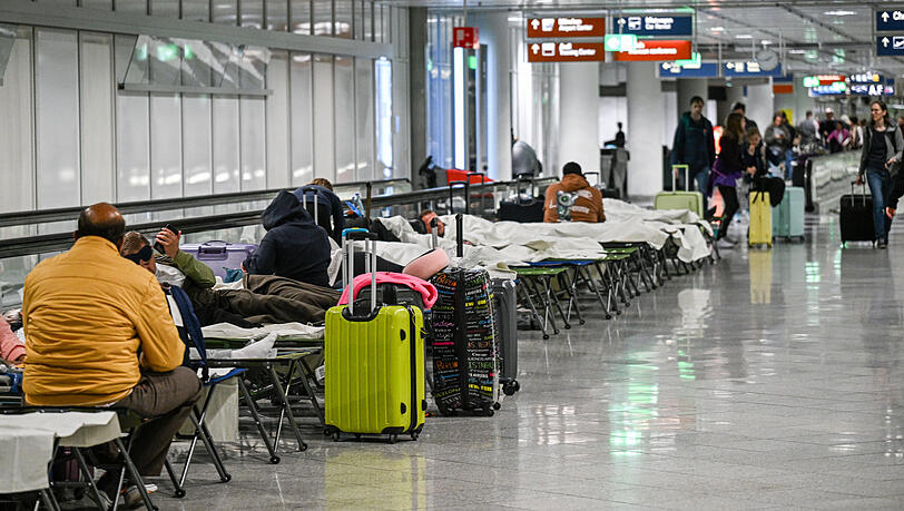 Menschen warten nach Drohnensichtungen und Flugausfällen in Flughafen München auf Feldbetten. Wegen Drohnensichtungen sind am Flughafen in München am Donnerstagabend rund 20 Flüge ausgefallen. +++ dpa-Bildfunk +++
