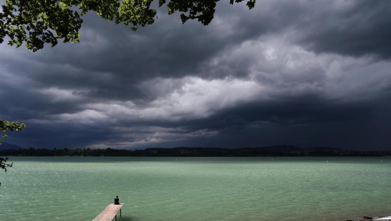Eine Wolkenfront türmt sich hinter dem noch im Sonnenschein liegenden Forggensee an dessen Ufer ein Mann sitzt. Foto: Karl-Josef Hildenbrand Eine Wolkenfront türmt sich hinter dem noch im Sonnenschein liegenden Forggensee an dessen Ufer ein Mann sitzt. Foto: Karl-Josef Hildenbrand