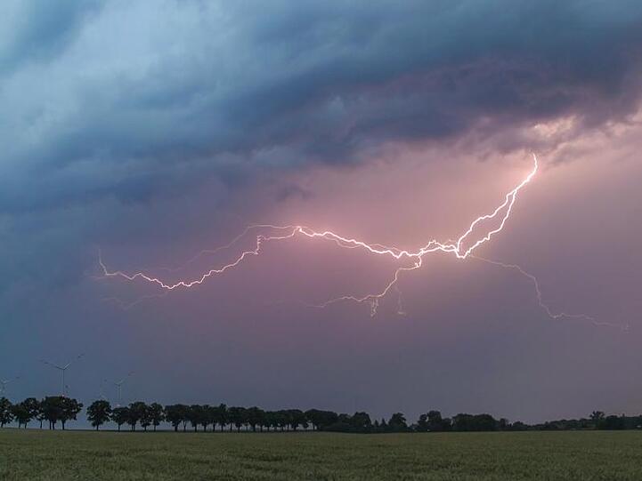 Ein Blitz erhellt den Abendhimmel über einem Feld. Foto: Patrick Pleul/dpa-Zentralbild/ZB/Symbolbild