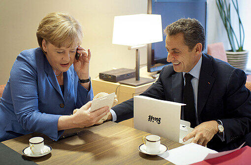 Baby-Geschenk: Angela Merkel überreicht Sarkozy hinter den Kulissen einen Teddybären für die kleine Giulia.
