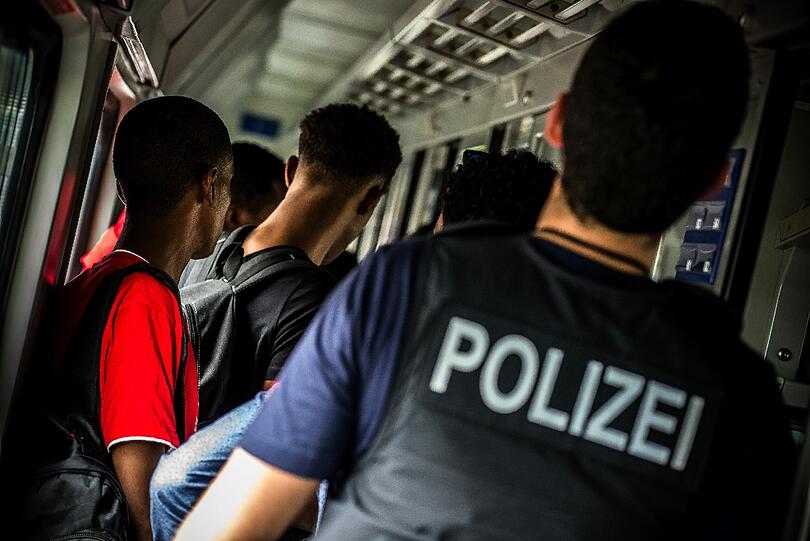 Der Bundespolizist Bastian K. geleitet am 09.09.2014 im gestoppten Eurocity in Rosenheim (Bayern) zahlreiche Flüchtlinge in Richtung Bahnsteig. Der sprunghafte Anstieg der Flüchtlingszahlen in Deutschland stellt die Bundespolizei vor große Herausforderungen.