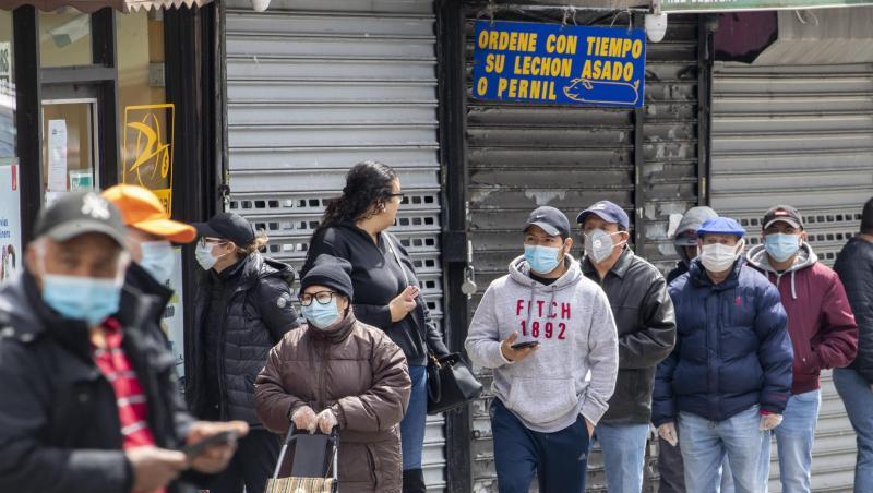Menschen mit Mundschutz stehen in einer Schlange vor einem Lebensmittelgeschäft im New Yorker Stadtteil Queens. Menschen mit Mundschutz stehen in einer Schlange vor einem Lebensmittelgeschäft im New Yorker Stadtteil Queens.