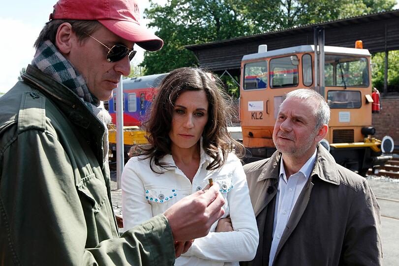 Die Schauspieler Nina Kunzendorf und Joachim Krol (r.) alias Tatort-Kommissare Conny Mey und Frank Steier schauen sich während eines Drehtermins zusammen mit Regisseur Lars Kraume (l.) authentische Munition an.