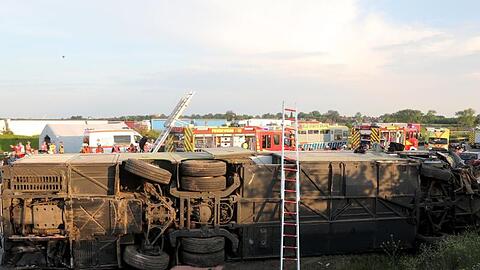 Einsatzkräfte der Feuerwehr stehen an der Unfallstelle neben dem verunglückten Bus. Der Bus überschlug sich zwischen den Anschlussstellen Leipzig-West und Bad Dürrenberg. Anschließend blieb das Fahrzeug auf der Seite liegen.