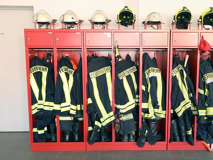 Jacken und Helme der Feuerwehr hängen in einem Schrank. Foto: Bernd Wüstneck/zb/dpa/Symbolbild