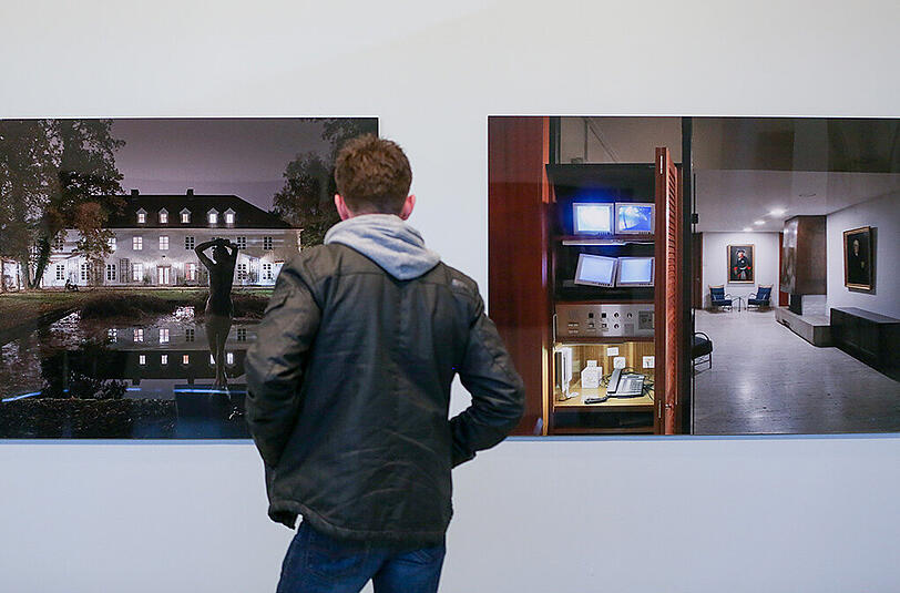 Ein Mann betrachtet am 23.03.2016 in Hamburg in der Ausstellung "Unheimlich - Der Bundesnachrichtendienst 1956 - 2016" zwei Fotos die Gebäude und Räume der BND-Zentrale in Pullach zeigen.