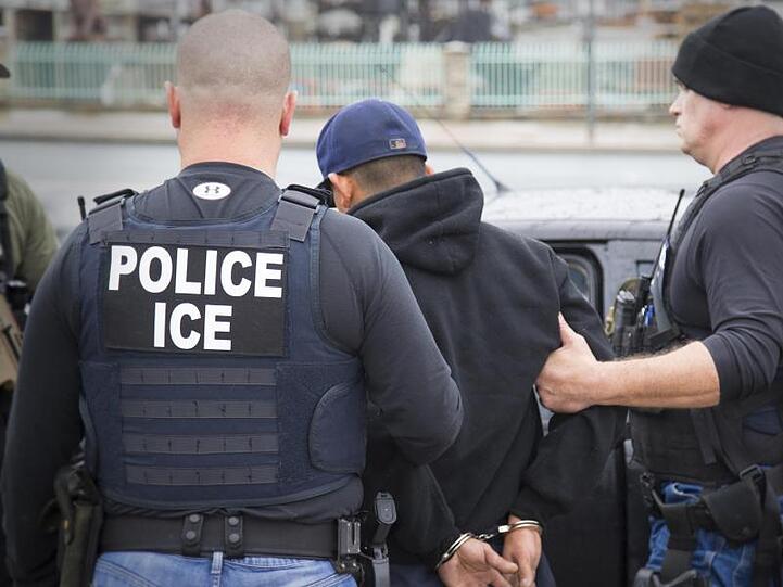 Polizisten der US-Immigration and Customs Enforcement Zollbehörde führen bei einer früheren Aktion einen Festgenommenen ab. Zurzeit gibt es keine Hinweise darauf, dass es am Sonntag zu Festnahmen im großen Stil kam.