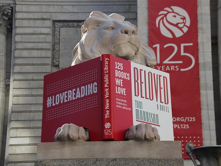 Der Löwe "Patience" liest das Buch "Menschenkind" von Tony Morrison.
