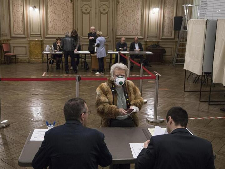 Eine Wählerin mit Atemschutzmaske registriert sich in einem Wahllokal in der französisch-italienischen Grenzstadt Menton.