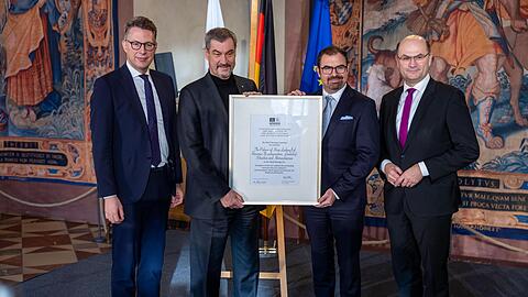 Die Freude ist gro&szlig; bei (v.l.) Bayerns Kunstminister Markus Blume, Ministerpr&auml;sident Markus S&ouml;der, Staatsminister im Ausw&auml;rtigen Amt Florian Hahn und Finanz- und Heimatminister Albert F&uuml;racker. Sie halten die Welterbe-Urkunde der M&auml;rchenschl&ouml;sser Ludwigs II. in den H&auml;nden.