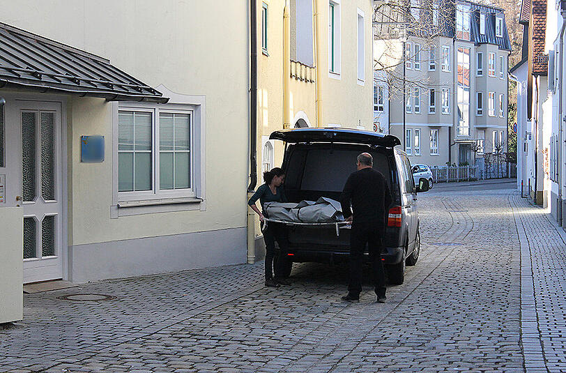 Bestatter tragen die Leiche des ermordeten Mitbewohners aus dem Haus.