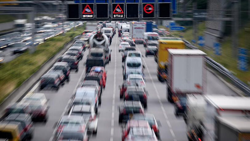 Zähfließender Verkehr während auf einer Anzeigetafel über der Autobahn vor Stau gewarnt wird.