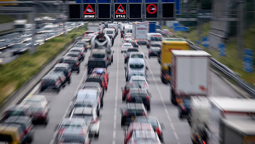 Zähfließender Verkehr während auf einer Anzeigetafel über der Autobahn vor Stau gewarnt wird. Zähfließender Verkehr während auf einer Anzeigetafel über der Autobahn vor Stau gewarnt wird.