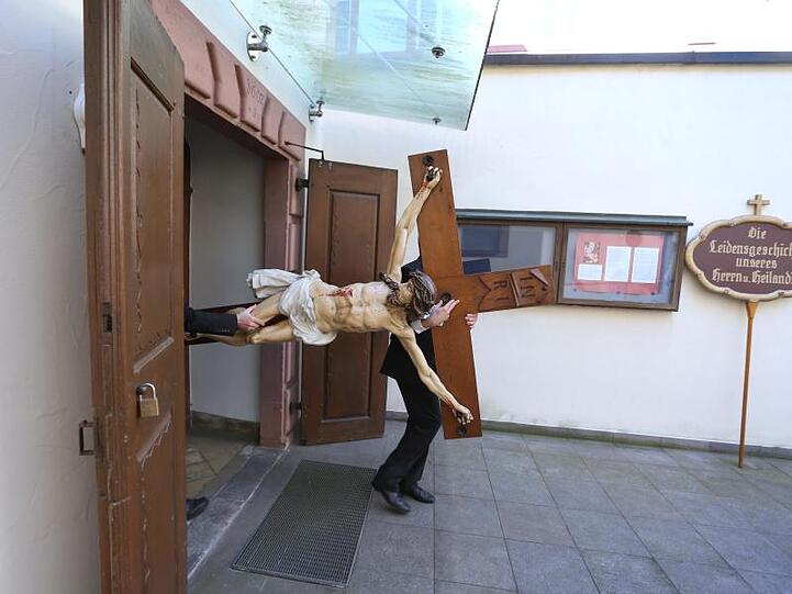 Angehörige der Maurerzunft tragen vor Beginn der Karfreitagsprozession in Lohr am Main ein Kreuz aus der Kapuzinerkirche.