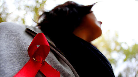 Eine Frau trägt eine Aids-Schleife an der Jacke. Dank moderner Medikamente ist ein positiver HIV-Test längst kein Todesurteil mehr.