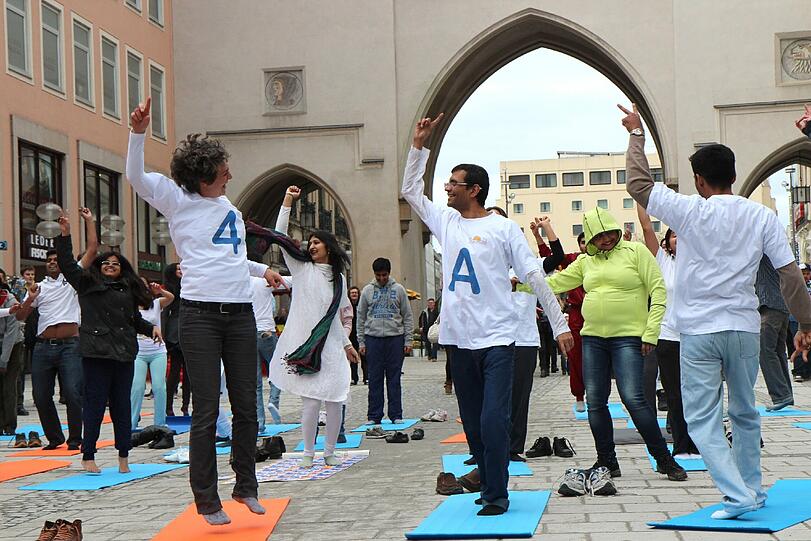 Hopsen und Dehnen in der Fußgängerzone: Am Stachus haben sich Yoga-Fans zu einem Flashmob unter freiem Himmel verabredet. Die Bilder.