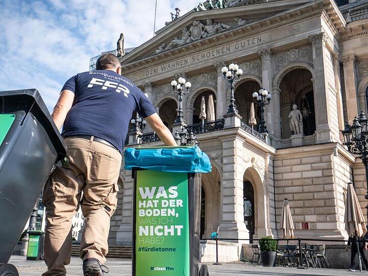 Am Morgen nach den Krawallen stellt ein Mitarbeiter der Stadtreinigung vor der Alten Oper geleerte Mülltonnen auf.
